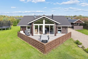 A modern house with a deck, large windows, and a covered patio area. - Lovely holiday home with hot tub in Skaven Strand (Tarm)