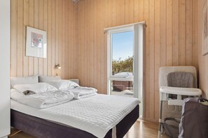 A bedroom with a bed, a chair, and a view of the outdoors. - Lovely holiday home with hot tub in Skaven Strand (Tarm)