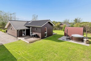 A modern house with a patio, a hot tub, and a well-maintained lawn. - Lovely holiday home with hot tub in Skaven Strand (Tarm)