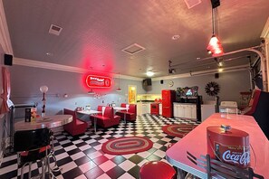 Ein Diner im Retro-Stil mit Schachbrettfußboden, roten Sitzecken und einem Coca-Cola-Spender.