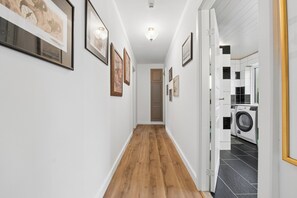 A hallway with wooden flooring, white walls, and framed artwork. - Cozy and spacious house (Vrå)