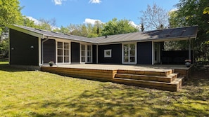 A two-story house with a covered porch and a small deck. - Architect-designed luxury summerhouse in Ordrup (Fårevejle)