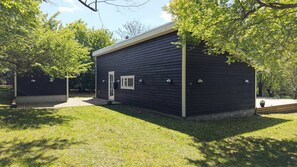 A single-story building with a dark exterior, a door, and a small window. - Architect-designed luxury summerhouse in Ordrup (Fårevejle)