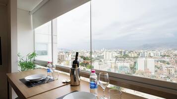 Une table à manger avec vue sur la ville, une bouteille d’eau, un verre à vin et une bouteille d’alcool.