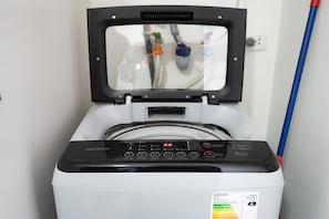 A front view of a washing machine with a digital control panel and a transparent door. - Connect Apartments by Vibrant (Barranco)