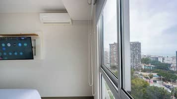Een hotelkamer met een groot raam, een bed, een wandtelevisie en een airconditioner.