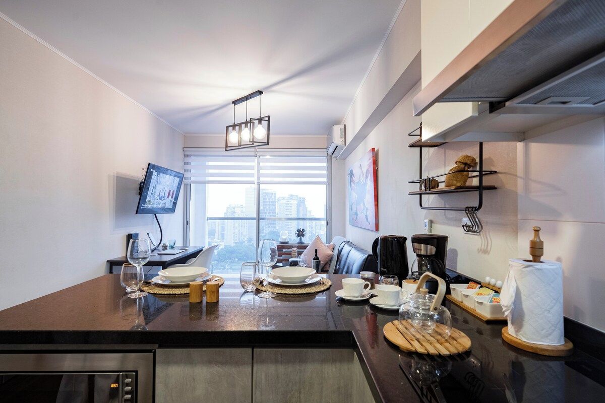 Cozinha moderna com área de jantar, máquina de café e vista para a cidade.