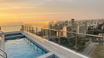Una piscina en la azotea con vistas a la ciudad al atardecer.
