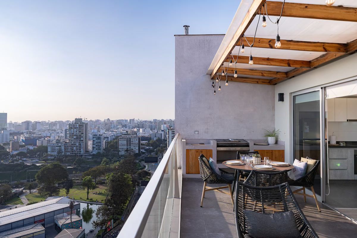 Een balkon met uitzicht op de stad, een tafel met stoelen en een kitchenette.