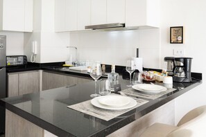 A modern kitchen with a black countertop, white cabinets, and a coffee maker. - Connect Apartments by Vibrant (Barranco)