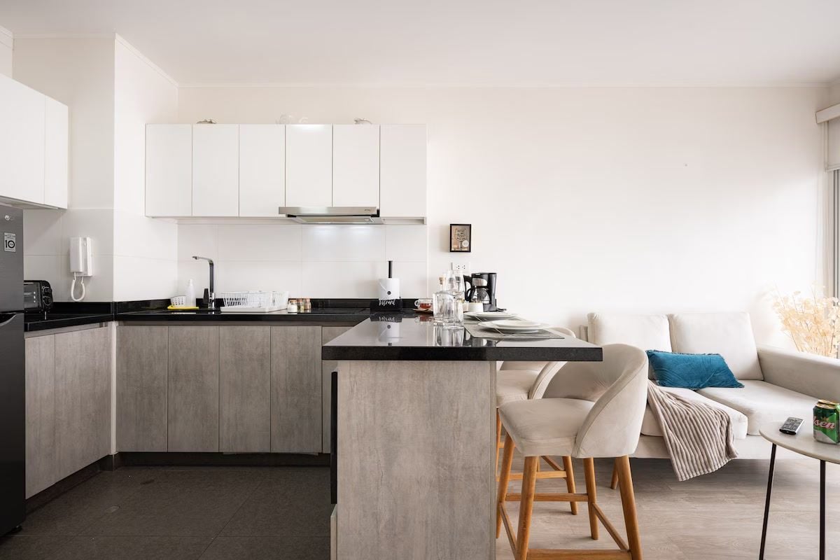 A modern kitchen with a central island, white cabinetry, and a grey countertop.