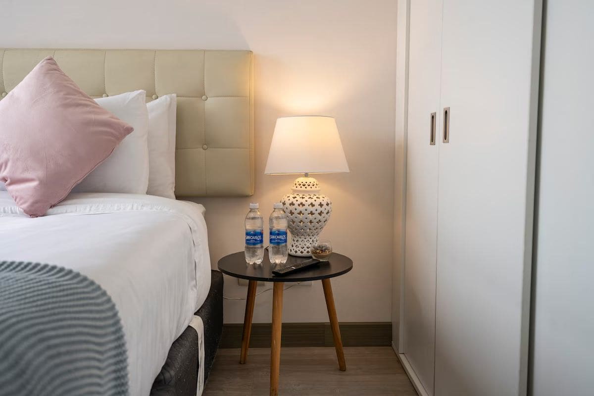 Una habitación de hotel con una cama, una mesita de noche con lámpara y un armario.