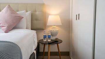 Una habitación de hotel con una cama, una mesita de noche con lámpara y un armario.