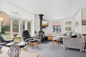 Ein modernes Wohnzimmer mit Kamin, bequemen Sitzmöglichkeiten und großen Fenstern.
