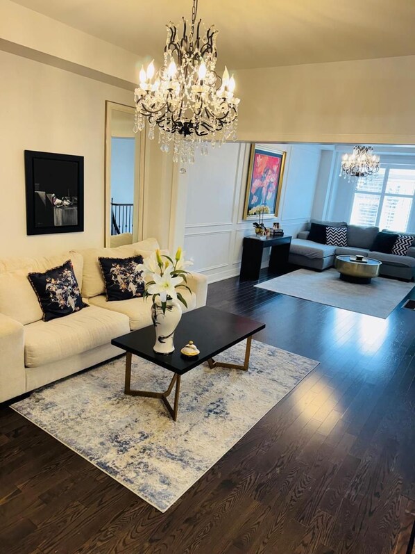 A modern living room with a chandelier, a sofa, a coffee table, and a rug.
