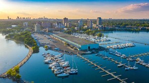 A marina with boats docked, a large building, and a city skyline in the background.