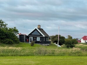 A black house with a white roof, a chimney, and a flagpole. - Cozy cottage by the Trend River (Løgstør)