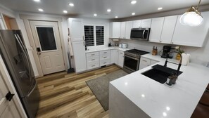 Una cocina moderna con armarios blancos, un refrigerador de acero inoxidable, un microondas y una estufa a gas.