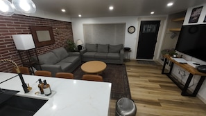 Ein modernes Wohnzimmer mit einer Eckcouch, einem runden Couchtisch und einer TV-Bank mit Flachbildfernseher.