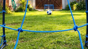 Un parcours d’obstacles bleu, composé de cordes, avec un ballon de football sur une pelouse.