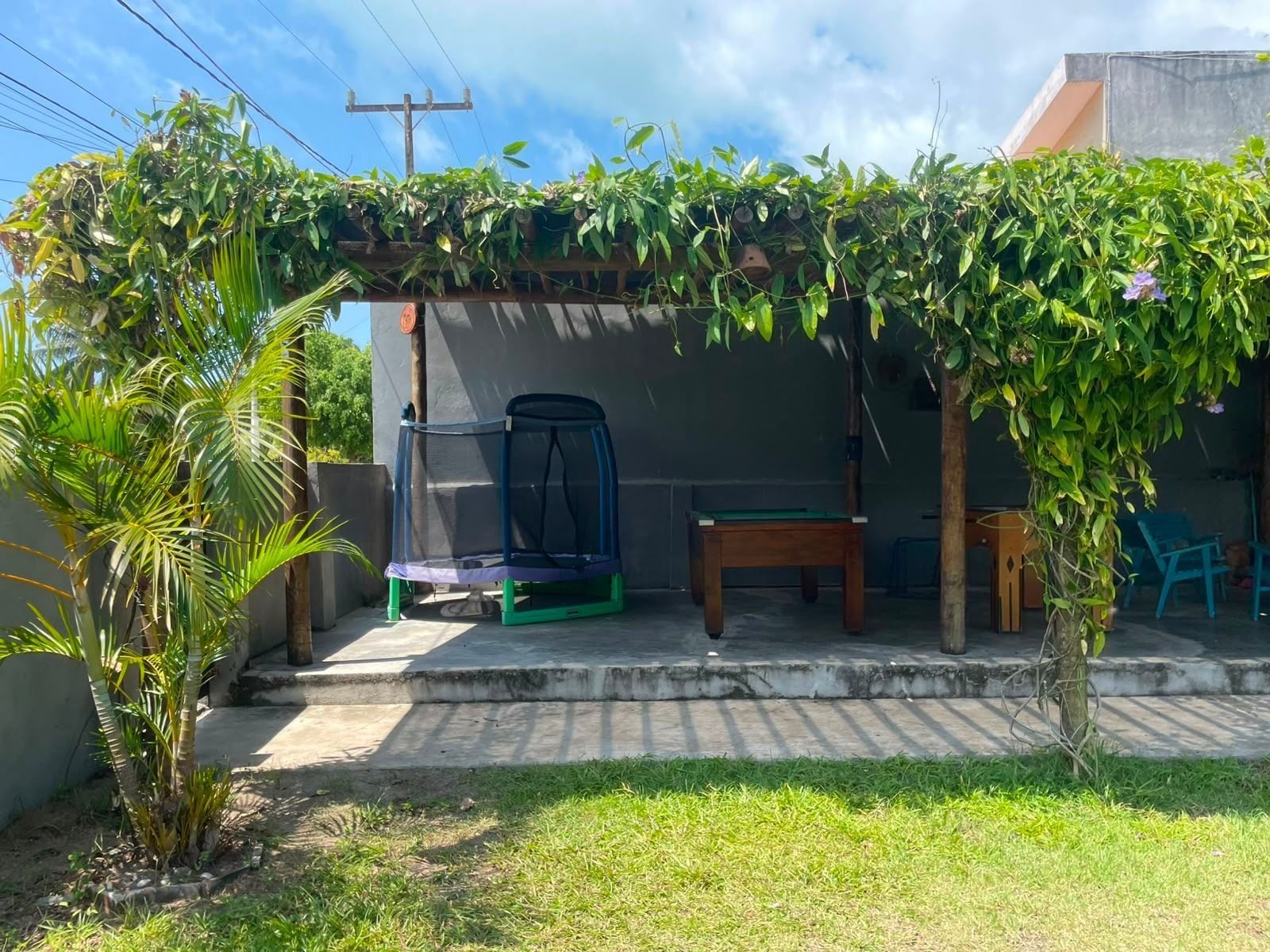 Un espace extérieur abrité comprenant un trampoline, une table et un banc.