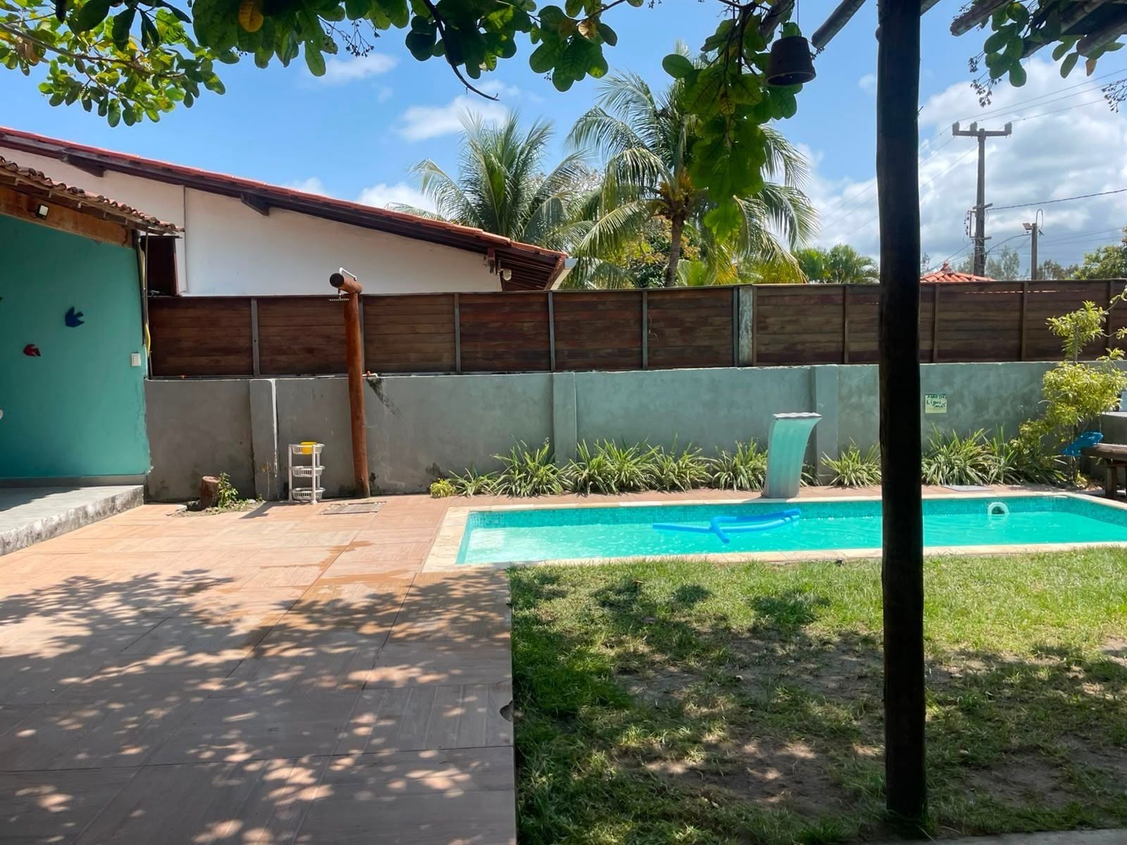 A backyard with a swimming pool, a wooden fence, and a house with a tiled roof.