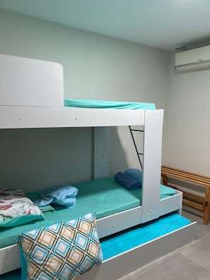 A bunk bed with a green mattress and a patterned pillow.