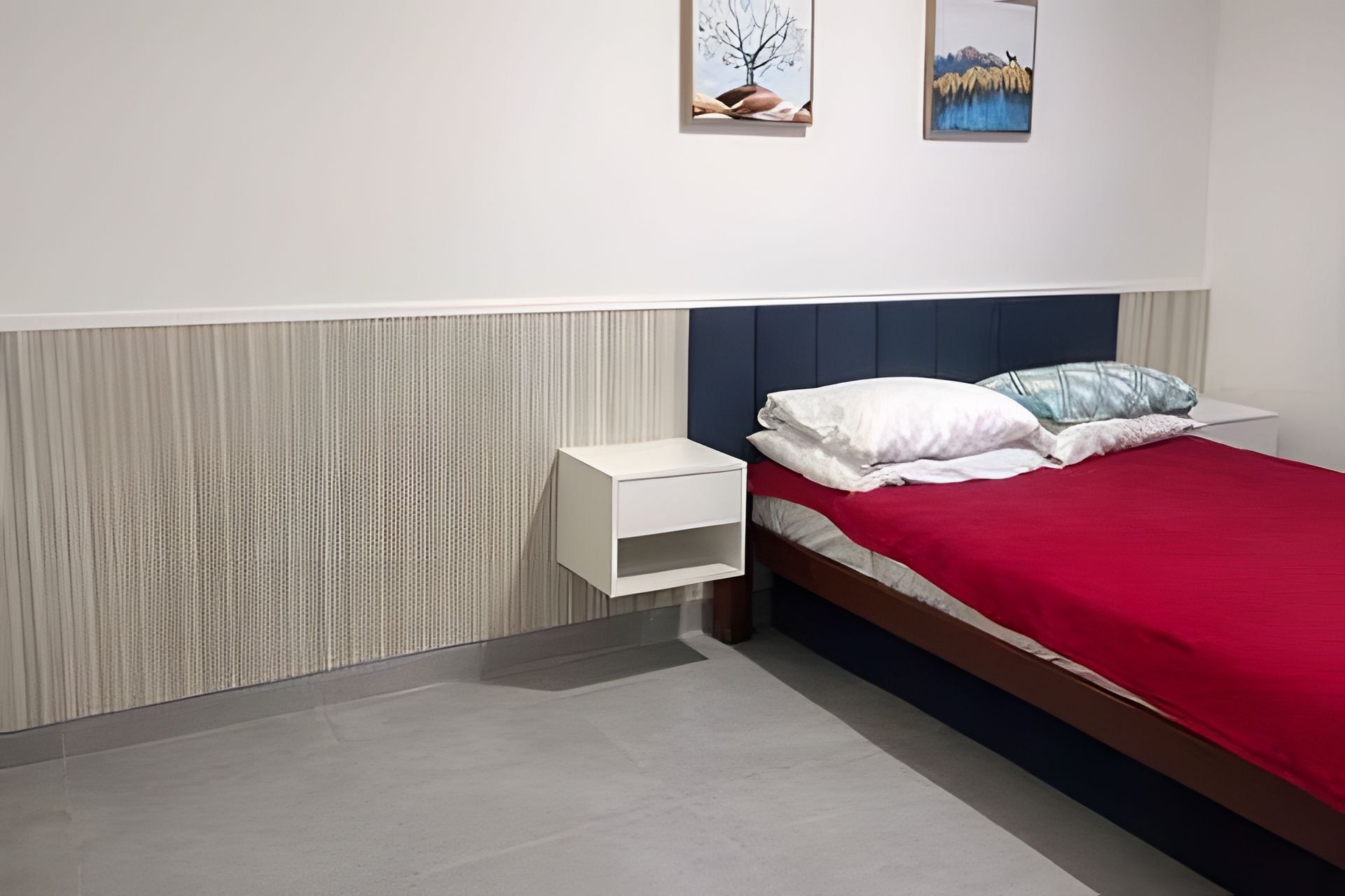 Une chambre à coucher comprenant un lit, une table de chevet et une œuvre d’art accrochée au mur.