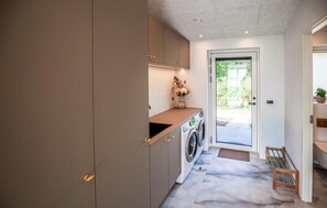 A laundry area with a washing machine, cabinets, and a door leading outside. - 4 bedroom cozy home in Thyholm (Thyholm)