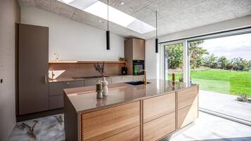 Una cucina moderna con un'isola grande, elettrodomestici integrati e vista su un paesaggio verde.