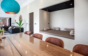Ein moderner Essbereich mit einem langen Holztisch, Lederstühlen und einer integrierten Bank mit Kissen.