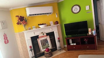 Een woonkamer met een open haard, een televisie en een groene wand.