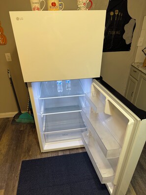 An open refrigerator with a 'Fresh Zone' label, a broom, and a mop on the floor. - THE HOUSE IN THE FOREST LA CASA EN EL BOSQUE (Garden City)