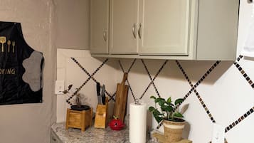 Een keuken met witte kastjes, een granieten aanrechtblad en een spatwand met een geometrisch patroon.