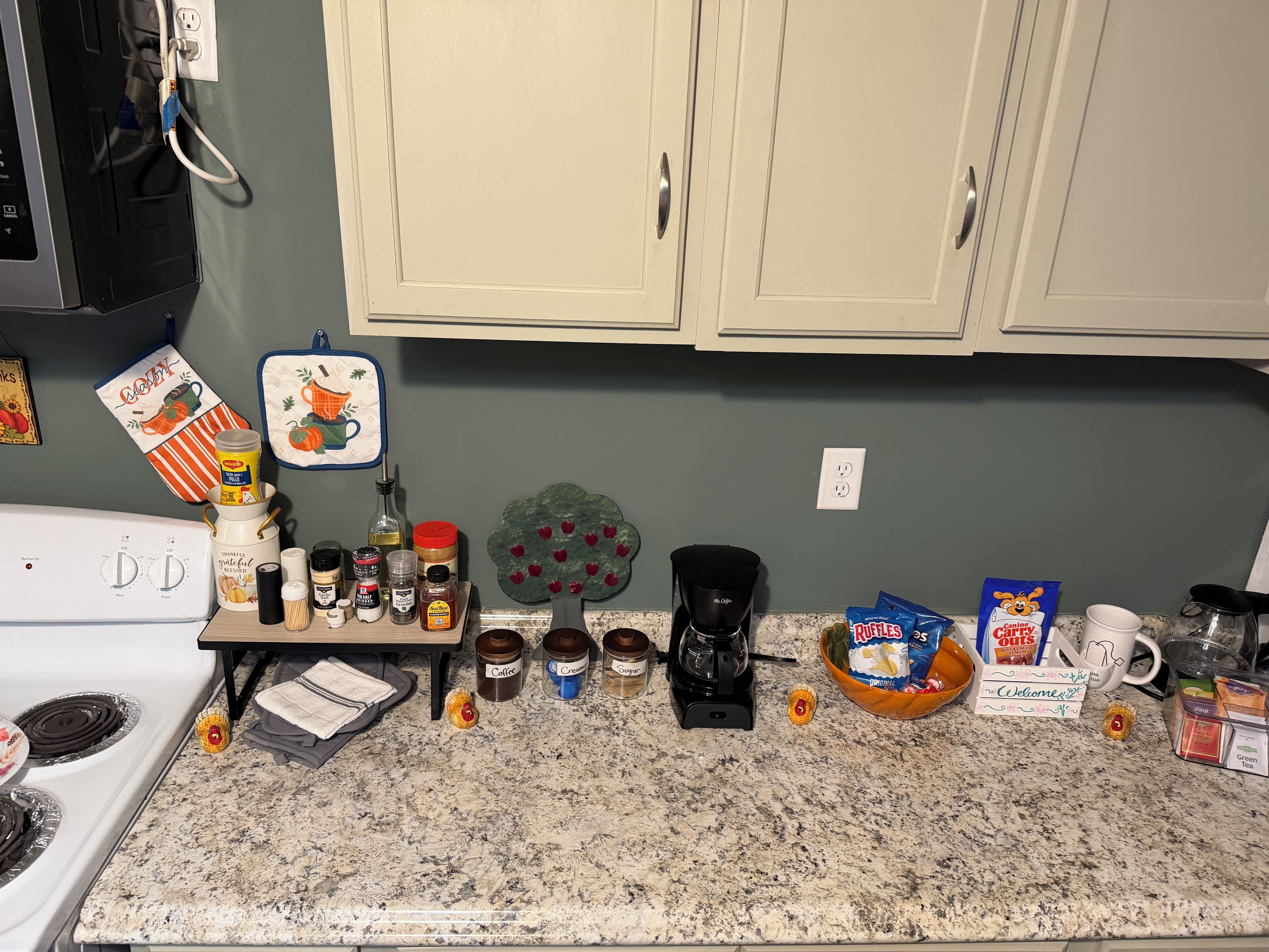 A kitchen counter with various items including a coffee maker, a bowl of cereal, and a coffee mug.