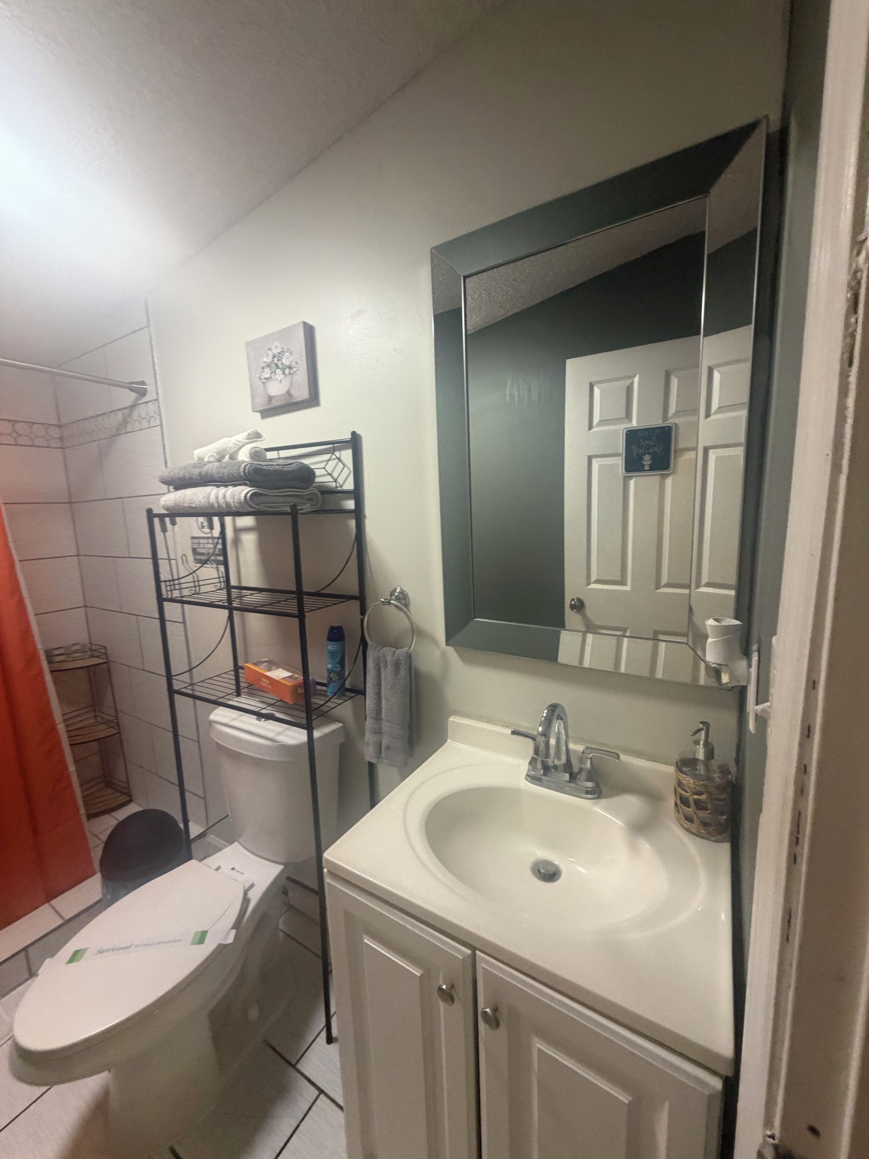 A bathroom with a toilet, sink, and a towel rack.