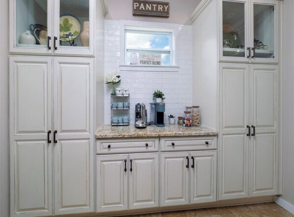 Una cocina con muebles blancos, encimera de granito y una ventana sobre el fregadero.