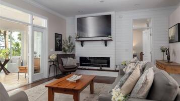 A modern living room with a flat-screen TV, fireplace, and comfortable seating.
