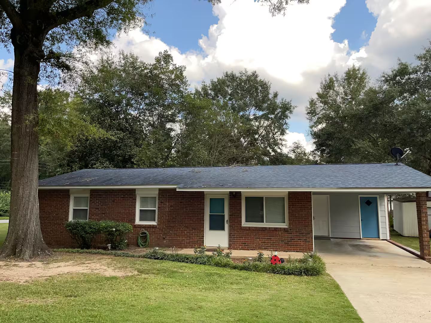 A single-story brick house with a dark roof, a front door, and a garage door.