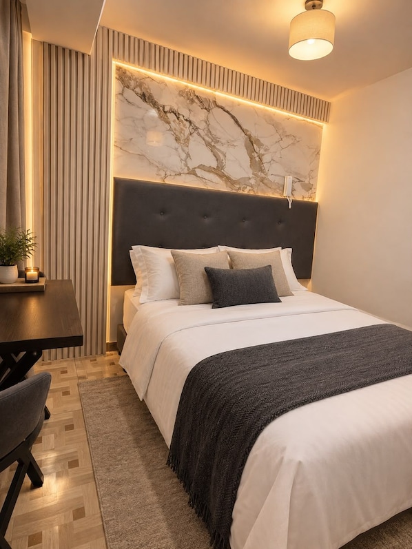 A modern bedroom with a marble headboard, a bedside table with a lamp, and a dark-toned bedspread.