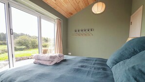 Una camera da letto con un letto, una finestra, una lampada a sospensione e vista sul verde all'esterno.
