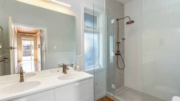 A modern bathroom with a glass shower enclosure, a double sink vanity, and a large mirror.
