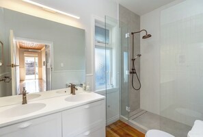 A modern bathroom with a glass shower enclosure, a double sink vanity, and a large mirror.