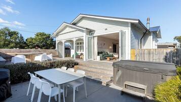 A house with a covered patio, outdoor seating, and a hot tub.