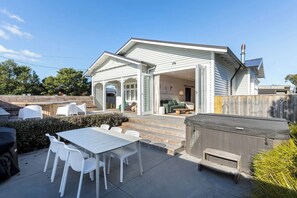 A house with a covered patio, outdoor seating, and a hot tub.