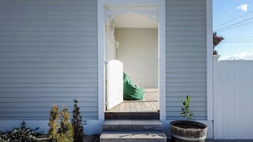 A house with a white exterior, a wooden front porch, and a green bag on the steps.