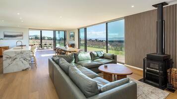 A modern living room with a large sofa, a dining area, and a fireplace.