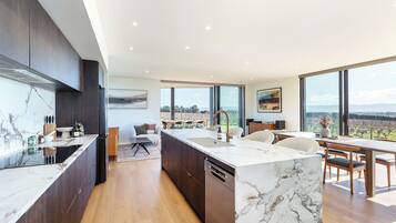 Une cuisine moderne dotée d’un plan de travail en marbre, de meubles en bois et d’un grand îlot central avec un évier.