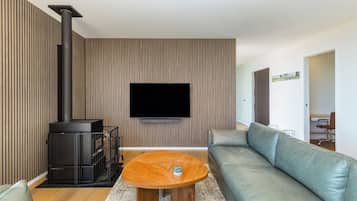 A modern living room with a sofa, a coffee table, a fireplace, and a flat-screen TV mounted on the wall.