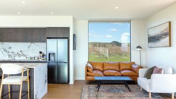 A modern kitchen with a marble backsplash, a stainless steel refrigerator, and a dining area with a white chair.